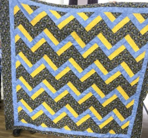 Deidre Hoggarth's quilt in yellow, blue, and leafy colors. Rail Fence Variation from The Weekend Quilter book. Machine pieced and quilted with kantha style hand quilting on the yellow patches.