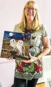 Kate Findlay holding her colourful and beautiful textile picture of owls.